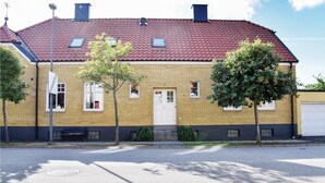 Un bâtiment à deux étages, construit en briques, avec un toit recouvert de tuiles rouges, une porte blanche et de nombreuses fenêtres.