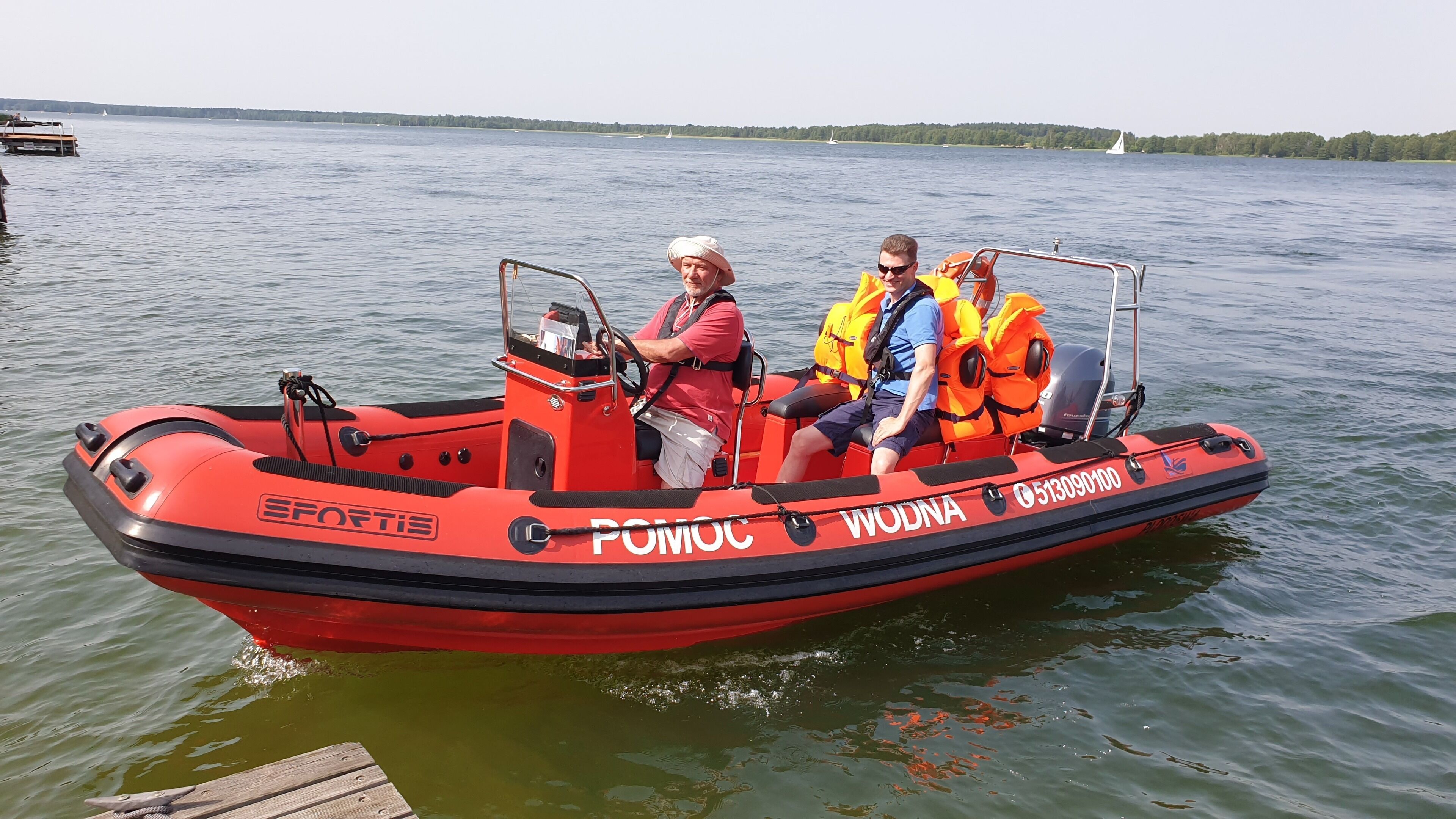 A red inflatable boat with the text "SPORTIS" and "POMOC" on the side, indicating it is a recreational vessel.