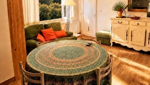 A cozy room with a green sofa, a round table with chairs, a wooden cabinet, and a window with curtains. - The waves of money - Le Lavandou (LE LAVANDOU)