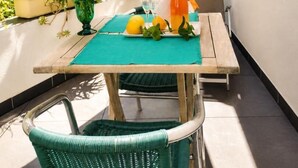 A patio table with a green mat, a wicker chair, and a potted plant with flowers. - The waves of money - Le Lavandou (LE LAVANDOU)