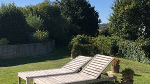 Une terrasse en bois avec deux chaises longues et des plantes en pot.