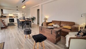 Un salon moderne avec un canapé en cuir marron, une table basse en bois et un coin repas comprenant une table et des chaises en bois.