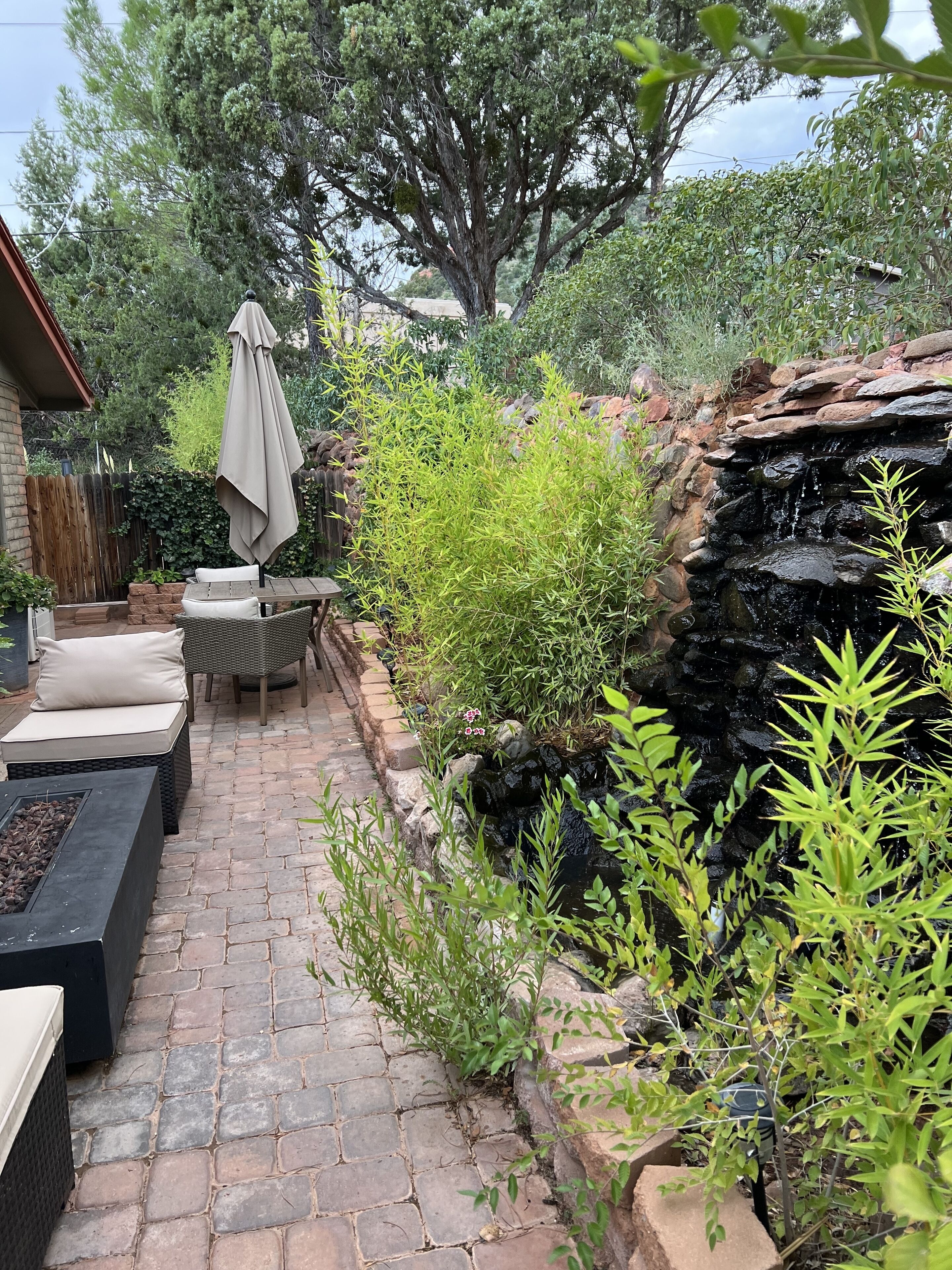 A patio area with a stone pathway, outdoor furniture, and a small waterfall feature.