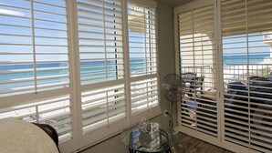 A room with large windows, a glass table, and a fan.