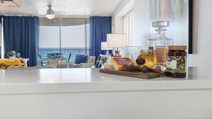A kitchen counter with various food items and a dining area with a view.