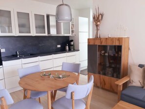 A modern kitchen with white cabinets, a black countertop, and a wooden dining table with chairs.