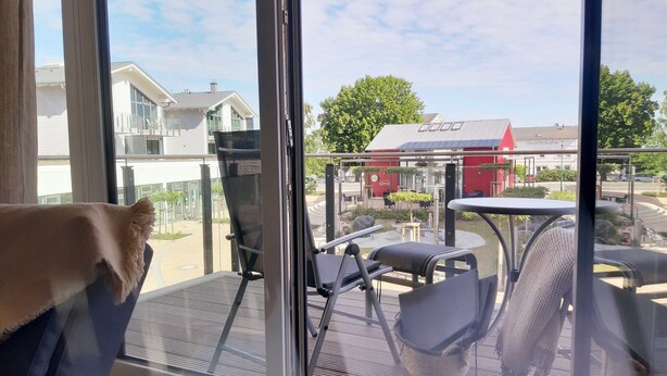 A balcony with a view of a red building and a parking area. - Haffduurn, Germany (Glowe)
