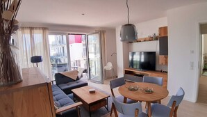 A modern living room with a sofa, dining table, chairs, and a TV. - Haffduurn, Germany (Glowe)