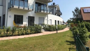 A modern multi-story residential building with balconies, a paved driveway, and a well-maintained lawn. - Haffduurn, Germany (Glowe)