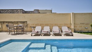 A pool area with lounge chairs and a table.