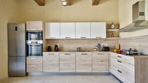 A modern kitchen with a built-in oven, a refrigerator, and wooden cabinets.