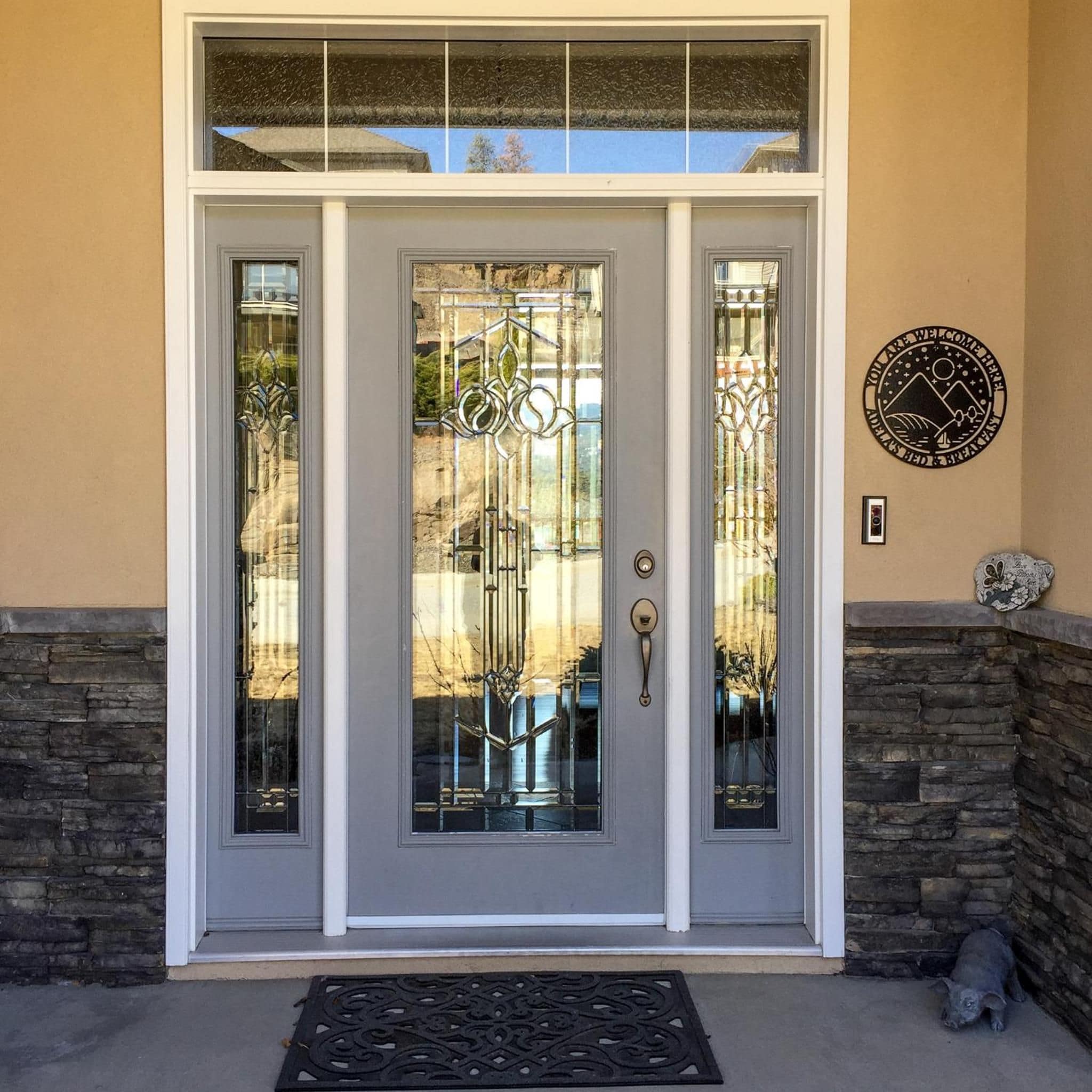 A front door with a glass panel, a metal handle, and a stone wall to the right.