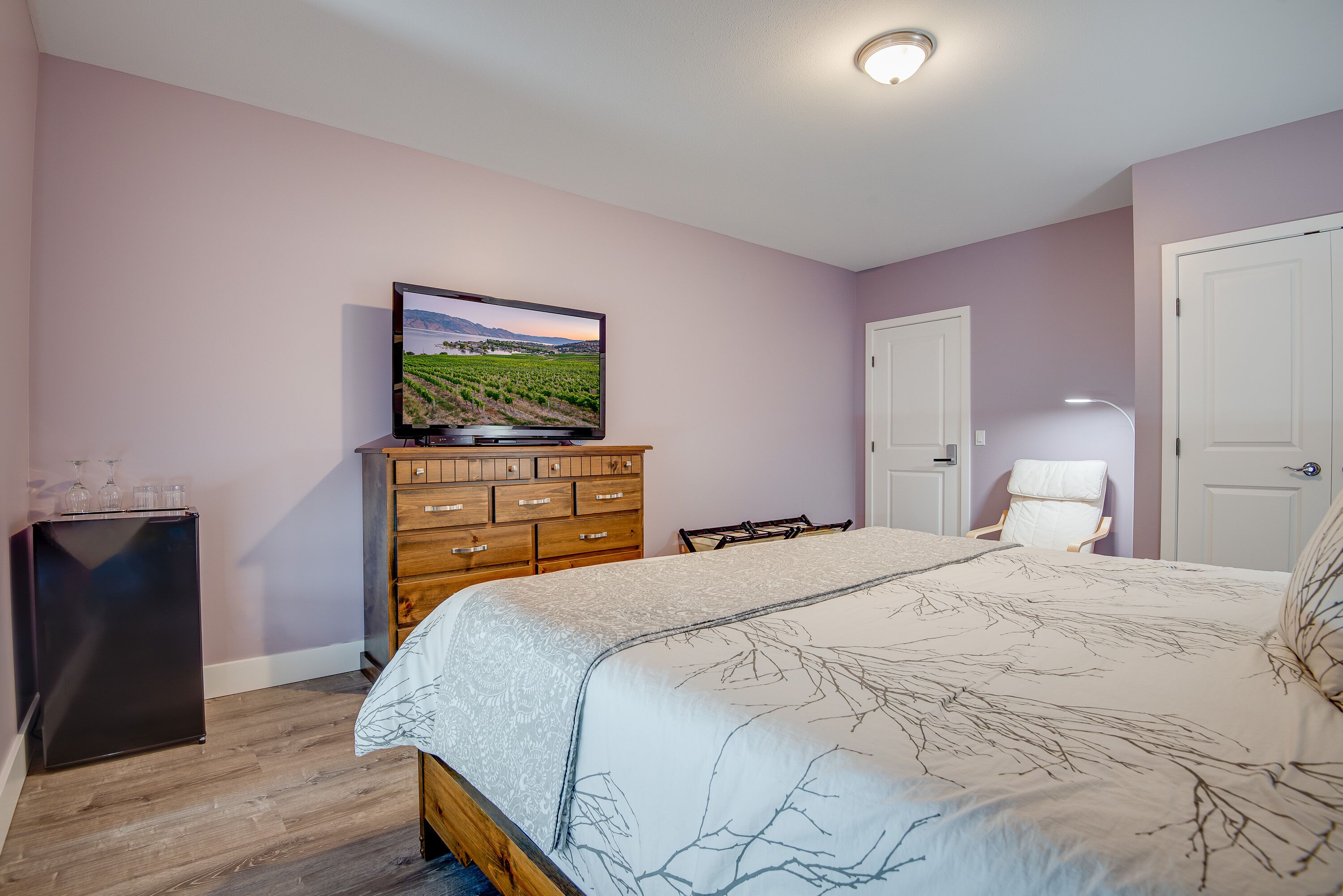 A bedroom with a bed, dresser, television, and a door.