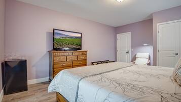 A bedroom with a bed, dresser, television, and a door.