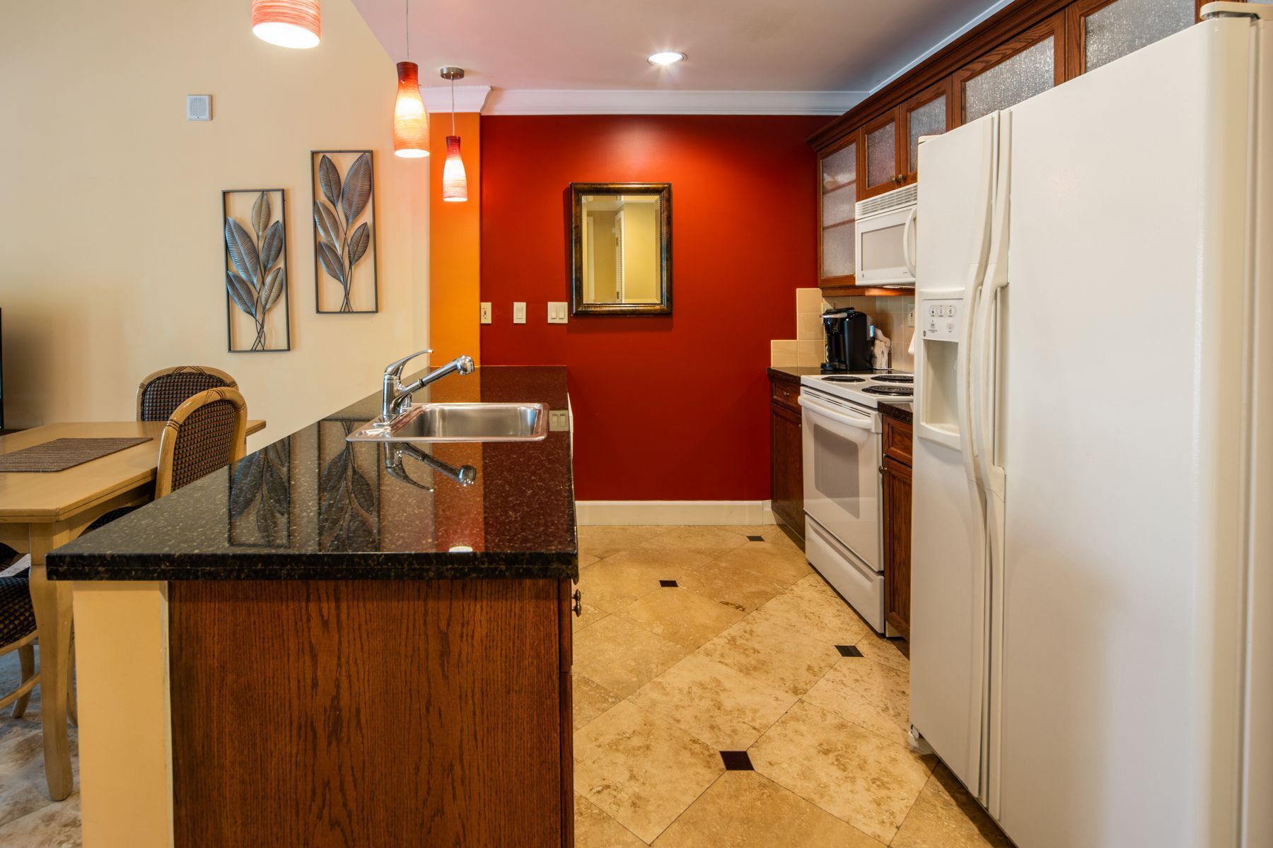 Una cocina compacta con una isla central, electrodomésticos blancos y una pared de acento roja.
