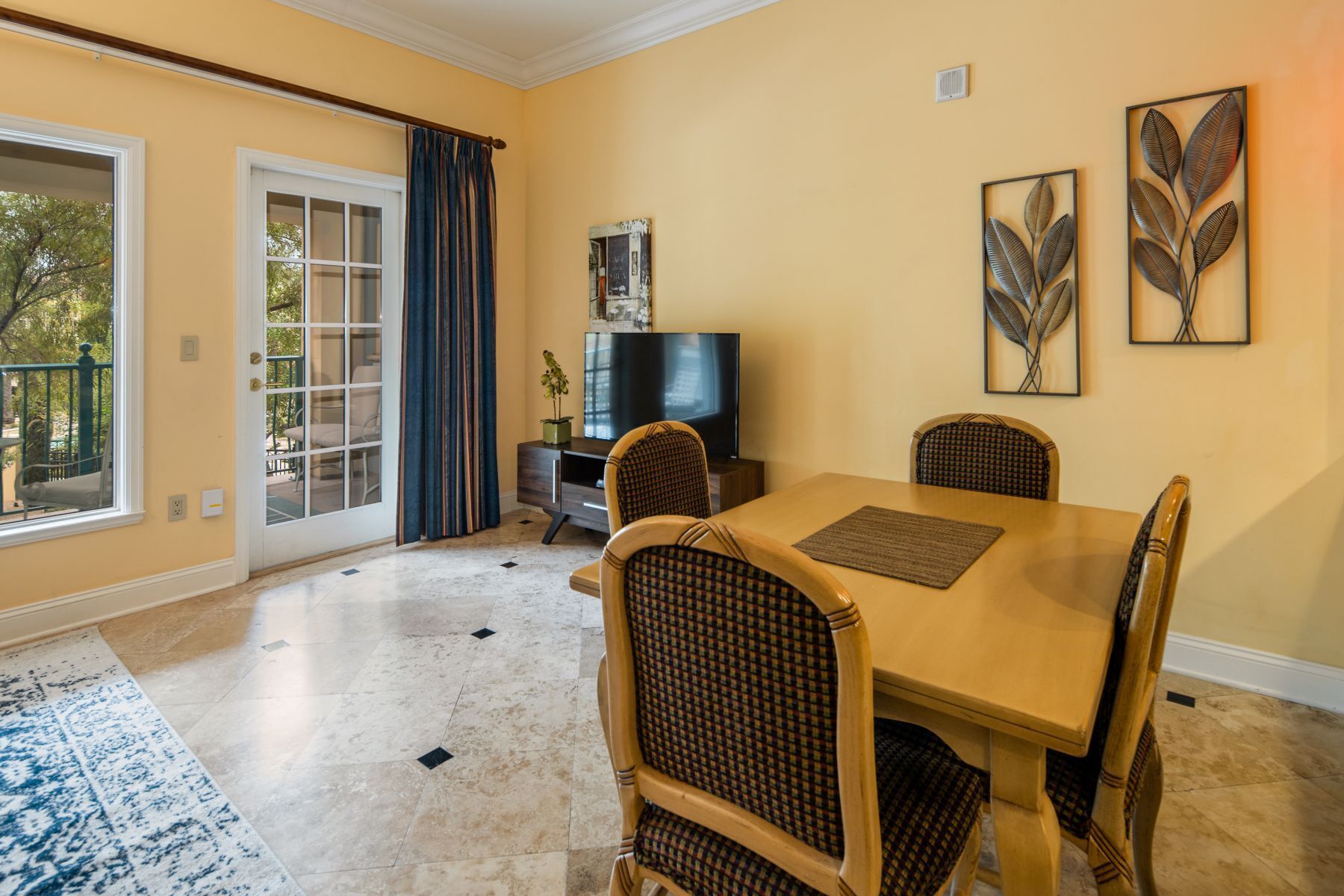 A dining area with a table, chairs, a television, and artwork on the wall.