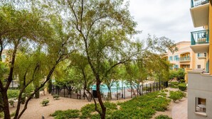 A courtyard with trees, a pool, and a building with balconies. - Gorgeous condo, super comfy, with view of the pool in Lake Las Vegas Village. (Henderson)