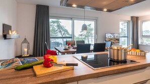 Een moderne keuken met een groot raam, een eethoek en uitzicht op bomen.
