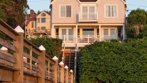 Une maison à deux étages avec un balcon, entourée de verdure.
