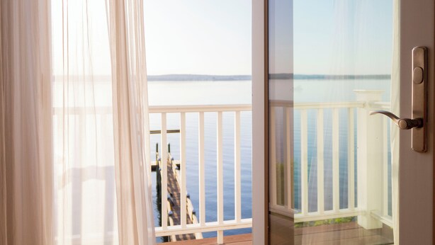 Un balcon avec vue sur la mer, une terrasse en bois et une balustrade blanche.