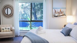 A hotel room with a large bed, a chair, a window with a view of the outdoors, and a wall-mounted mirror. - Noosa Heads Endless Summer Beach Retreat (Noosa Heads)
