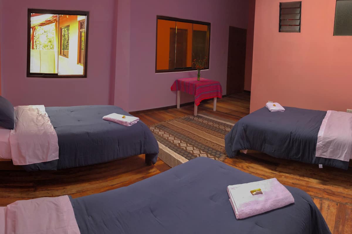 A room with three beds, a small table, and a window.