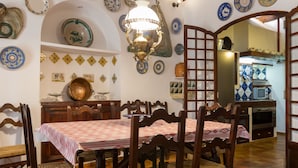 Uma área de refeições com uma mesa e cadeiras de madeira, decorada com pratos decorativos nas paredes.