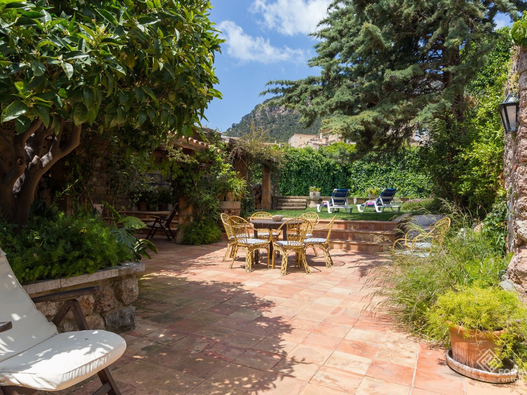 Une terrasse aménagée avec du mobilier d’extérieur, une table en pierre et une vue sur un paysage montagneux.