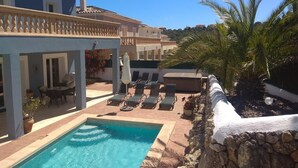 A pool area with lounge chairs and a stone wall. - Luxurious villa near beach: swimming pool (heatable), whirlpool, high speed WiFi (Cala Murada)