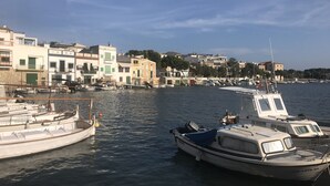 A marina with boats docked, a waterfront building complex, and a clear sky. - Luxurious villa near beach: swimming pool (heatable), whirlpool, high speed WiFi (Cala Murada)