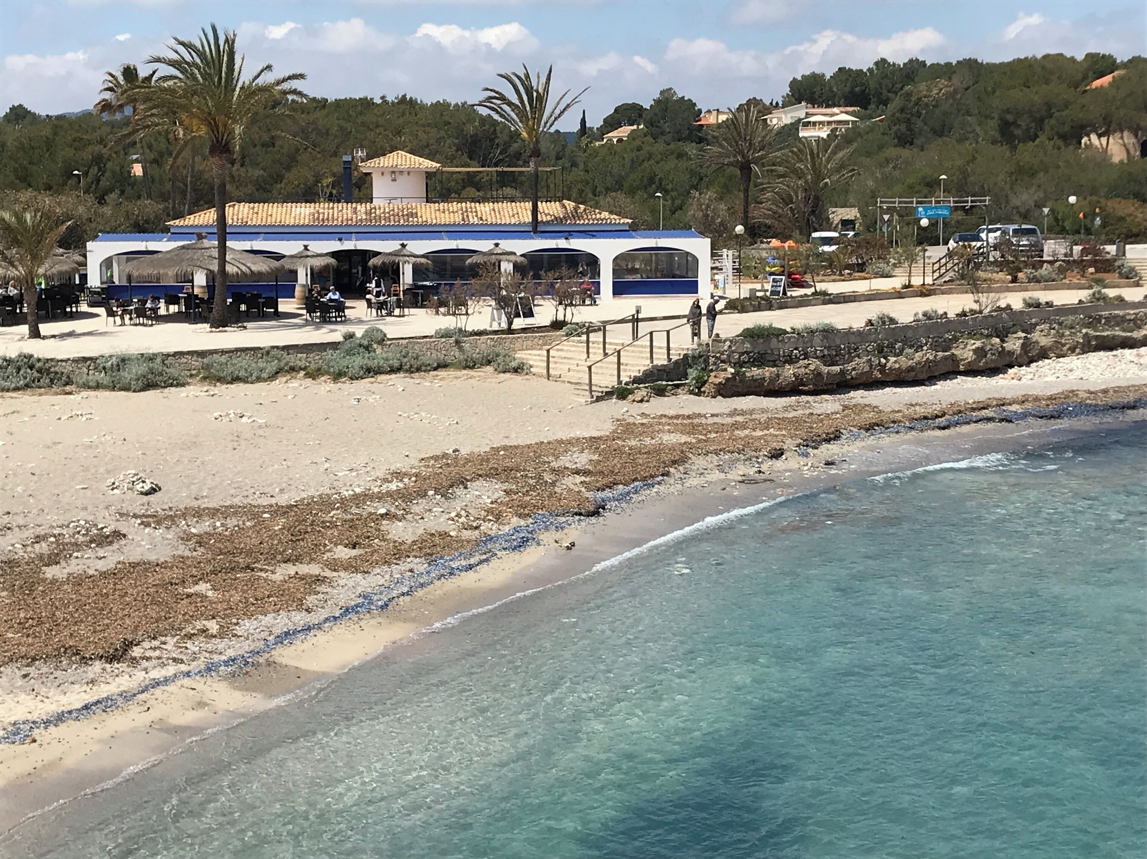 A beachside building with outdoor seating and a view of the sea.