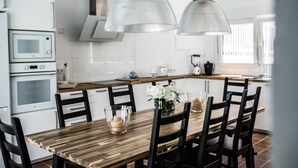 Eine moderne Küche mit weißen Geräten, einem Holzespeisetisch und schwarzen Stühlen.
