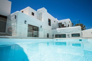 Un bâtiment moderne de couleur blanche, avec une piscine devant.