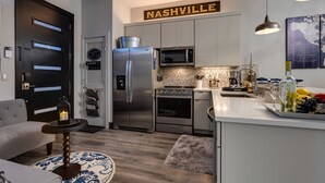 A modern kitchen with stainless steel appliances, a white countertop, and a 'Nashville' sign above. - Downtown Exquisite Couples Weekend Getaway+Parking (Nashville)