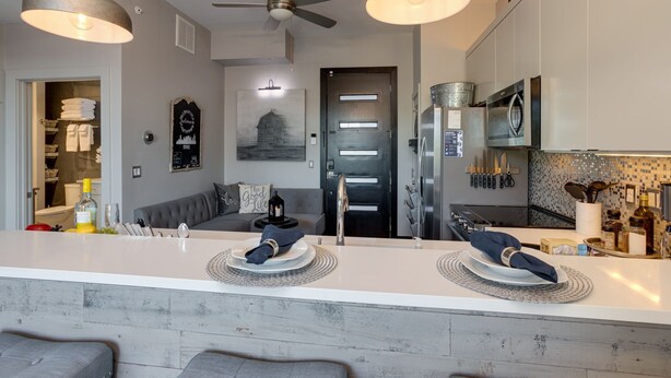 A modern kitchen with a central island, built-in appliances, and a dining area with a sofa and table. - Downtown Exquisite Couples Weekend Getaway+Parking (Nashville)