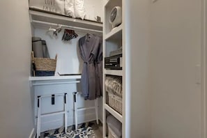 A white closet with shelves, a drying rack, and a hanging robe.