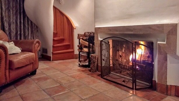 A living room with a fireplace, a spiral staircase, and a leather sofa.