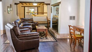 A spacious living room with a leather sofa, wooden coffee table, and a dining area with a wooden table and chairs.