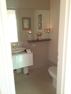 A bathroom with a sink, mirror, toilet, and two wall-mounted lights. - Malvern (Armadale)