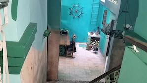 A staircase with a handrail, leading to a room with teal walls, a ship's wheel decoration, and a hanging lantern. - Ana y Alberto (Havana)