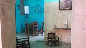 A room with a teal wall, a wooden table, and a chair. - Ana y Alberto (Havana)