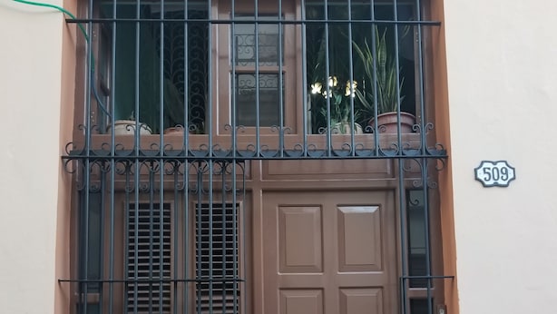 A brown door with a window above it, a metal gate, and a house number 509. - Ana y Alberto (Havana)
