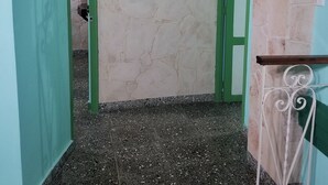 A narrow hallway with a green archway, a white wall with a textured pattern, and a metal railing on the right. - Ana y Alberto (Havana)