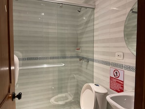 Un baño con cabina de ducha de vidrio, inodoro y lavabo.