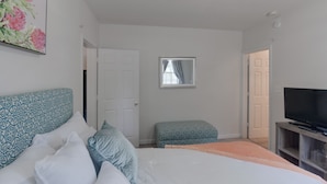 A bedroom with a bed, a television, and a window.