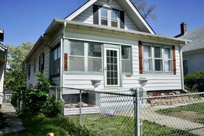 A two-story house with a front porch, a fenced yard, and a mailbox.