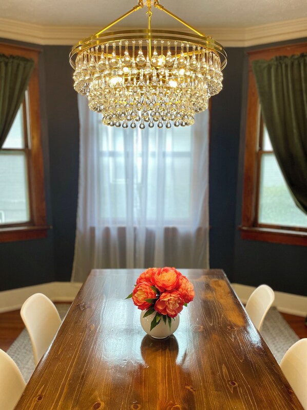 A dining room with a wooden table, a chandelier, and a vase of flowers.