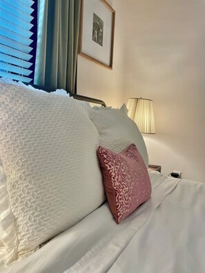 A neatly made bed with patterned pillows, a bedside lamp, and a framed picture on the wall.