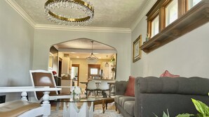 A living room with a dining area, a chandelier, and a sofa with a plant.