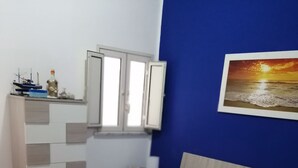 A bedroom with a bed, pillows, a quilt, and a nightstand. - Ludovica's dream house  (Bagheria)